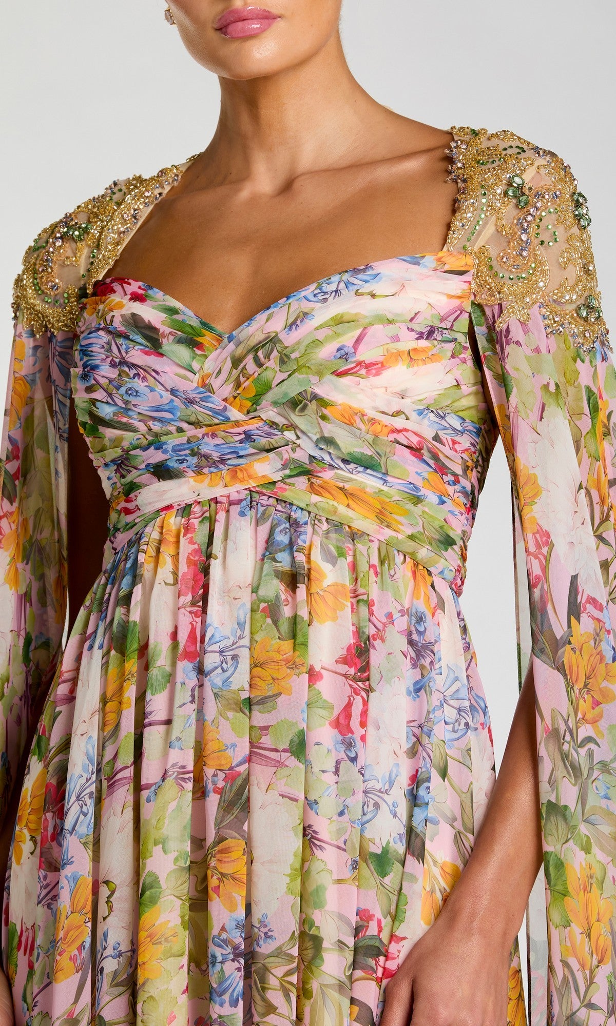 A woman in the Mac Duggal 11990 long formal dress, featuring floral chiffon, pleats, gold-embellished shoulders, and draped sleeves—an elegant choice for special occasions.